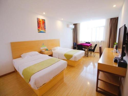 a hotel room with two beds and a desk at GreenTree Alliance Suzhou Zhangjiagang Nanfeng Town Hotel in Zhangjiagang