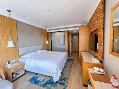 a bedroom with a large white bed and a television at Excemon Beach Hotel Beihai in Beihai