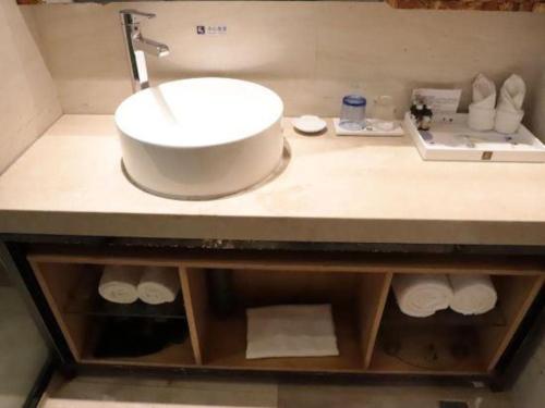 a bathroom counter with a sink and towels on it at Excemon Beach Hotel Beihai in Beihai