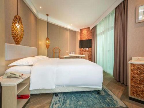 a bedroom with a large white bed and a desk at Excemon Beach Hotel Beihai in Beihai