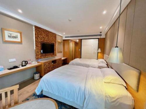 a hotel room with a large bed and a tv at Excemon Beach Hotel Beihai in Beihai