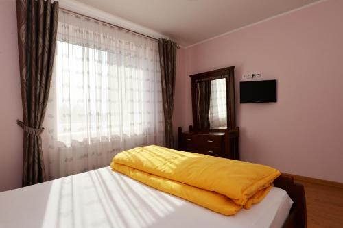 a bedroom with a bed with a yellow blanket on it at Apartamentai prie Alkos in Druskininkai