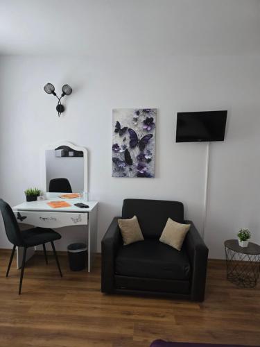 a living room with a black couch and a desk at Stephanovy Guest House in Sozopol