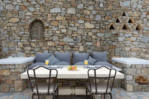 a table and chairs in front of a stone wall at Cova Mykonos Suites in Elia Beach