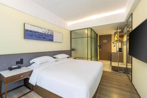 a bedroom with a large white bed and a bathroom at AURAYA BY SUNING NANJING XUZHUANG in Nanjing