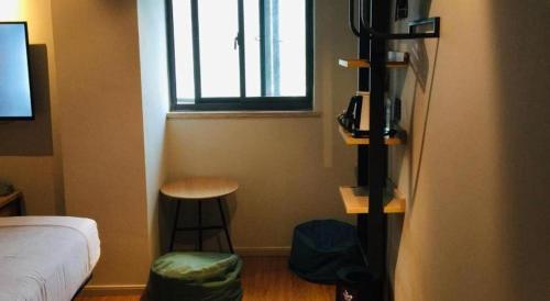 a bedroom with a bed and a stool and a window at YUNIK-Shanghai Zhongshan Park Yan'an Xi Road in Shanghai