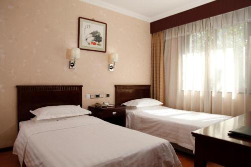 a hotel room with two beds and a window at Hujialou Hot Spring Hotel in Beijing
