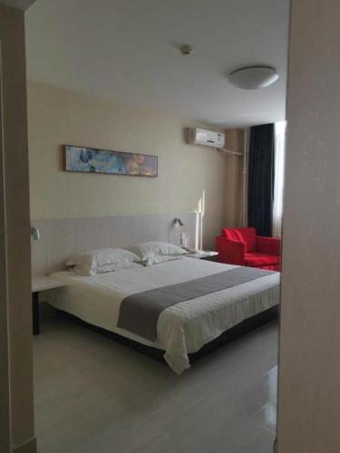 a bedroom with a large bed and a red chair at Zhangye Pinmu Hotel(Yuncheng Zhongyin Avenue Store) in Yuncheng