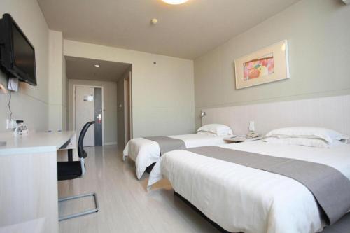 a hotel room with two beds and a flat screen tv at Zhangye Pinmu Hotel(Yuncheng Zhongyin Avenue Store) in Yuncheng