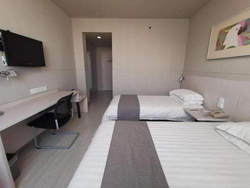 a hotel room with two beds and a desk at Zhangye Pinmu Hotel(Yuncheng Zhongyin Avenue Store) in Yuncheng