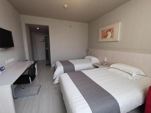 a hotel room with two beds and a desk at Zhangye Pinmu Hotel(Yuncheng Zhongyin Avenue Store) in Yuncheng