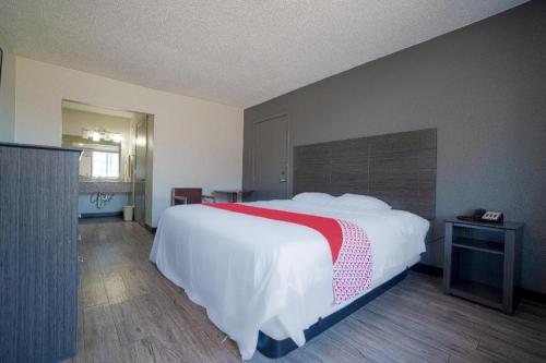 a bedroom with a large bed with a red and white blanket at Hotel Comfort Stay by OYO Texarkana East, AR I-30 in Whatley