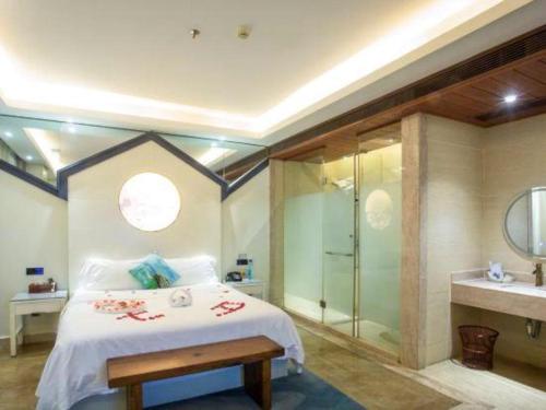 a bedroom with a bed and a shower and a sink at Huangma Holiday Nanhai Museum Hotel in Haikou