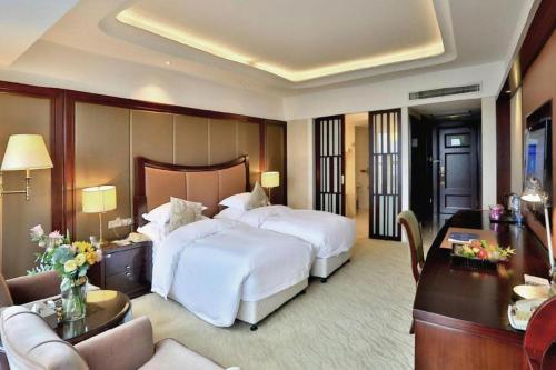 a hotel room with a large bed and a living room at Dongyang Narada Grand Hotel in Yiwu