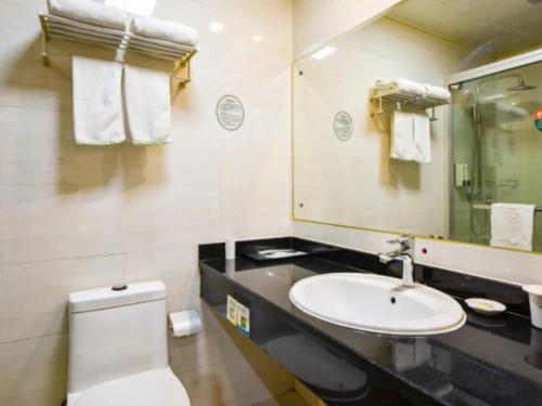 une salle de bain avec un lavabo, des toilettes et un miroir dans l'établissement GreenTree Inn Wuxi Changjiang North Road Jincheng Road Express Hotel, à Fangqian