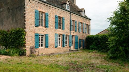 un vieux bâtiment en briques avec des volets bleus dans l'établissement La Colombière Maison Familiale avec piscine proche Tournus, à Ratenelle
