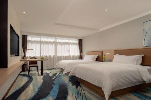 a hotel room with two beds and a television at GreenTree Inn Ganzhou Sankang Temple DaRunFa Express Hotel in Ganzhou