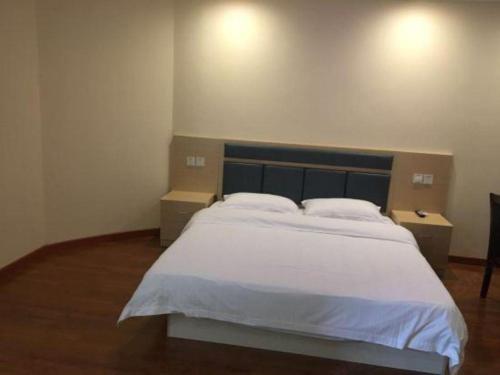 a bedroom with a large white bed with two tables at GreenTree Inn Wuhu Fangte Second Phase Nanxiang Wanshang Express Hotel in Wuhu