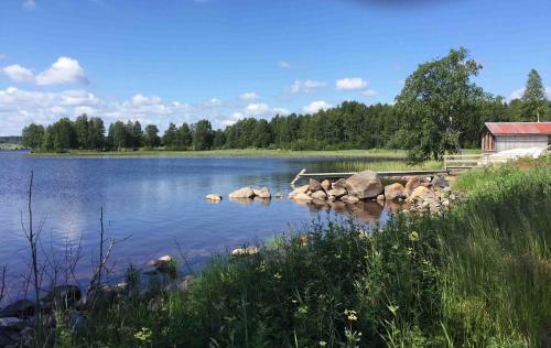 a view of a lake with rocks and a building at Villa Insikt Pensionat & Kursgård in Burträsk