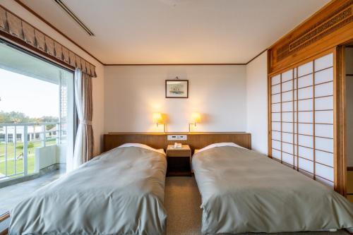 two beds in a room with a window at Coral Palms in Amami