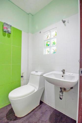 a green and white bathroom with a toilet and a sink at OYO 75314 Mountain Beach in Prachuap Khiri Khan