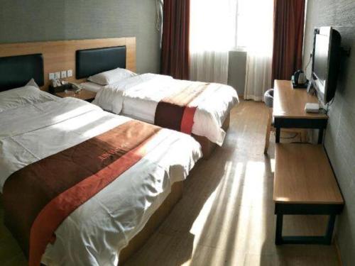 a hotel room with two beds and a television at Jun Hotel Jiangsu Nanjing Gulou District Gupinggang in Nanjing