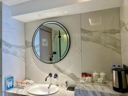 ein Badezimmer mit Waschbecken und Spiegel in der Unterkunft Zhangjiagang Jiangnan Garden Hotel in Xiwujieqiao