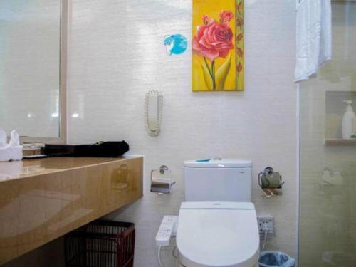 a bathroom with a toilet and a painting on the wall at Xiamen Airlines Quanzhou Hotel in Quanzhou