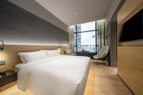 a large white bed in a room with a window at Opus Hotel Jiangmen in Jiangmen