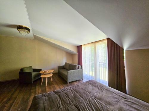 a bedroom with a bed and a couch and a table at Hotel resort Sedula in Skogalis