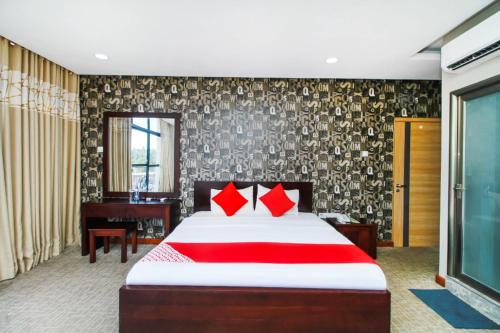a bedroom with a bed with red pillows and a piano at OYO 299 Randula Grand Venus Hotel in Katuwalamulla