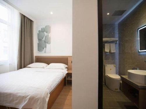 a bedroom with a bed and a bathroom with a sink at GreenTree Inn Chaoyang Shuangta District Bus Station in Chaoyang