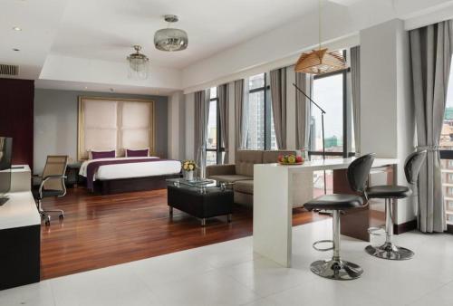 a hotel room with a bed and a living room at Essence Hotel-Phnom Penh in Phnom Penh