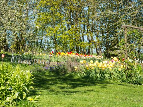 a garden with colorful flowers and a fence at Pyttegården Apartments in Gudhjem