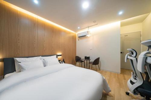 a bedroom with a large white bed and a table at Hotel Casa Suwon in Suwon