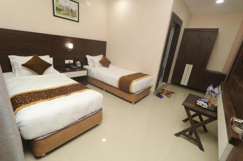 a hotel room with two beds and a table at Hotel Gajur Palace in Itahari