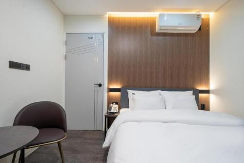 a bedroom with a white bed and a table and a chair at Hotel Casa Suwon in Suwon