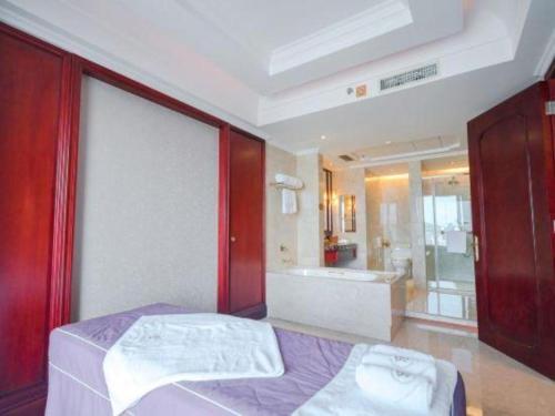a bedroom with a bed and a bath room with a tub at King Century Hotel in Zhongshan