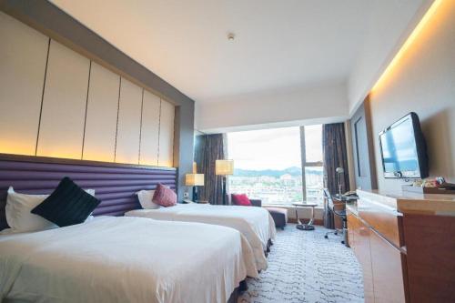 a hotel room with two beds and a flat screen tv at King Century Hotel in Zhongshan