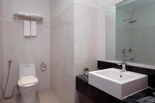a white bathroom with a sink and a toilet at Horison Nindya Semarang in Semarang
