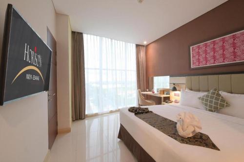 a hotel room with a large bed and a desk at Horison Nindya Semarang in Semarang
