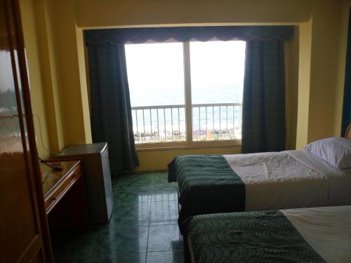 a hotel room with two beds and a window at Royal Crown Hotel عائلات فقط in Alexandria