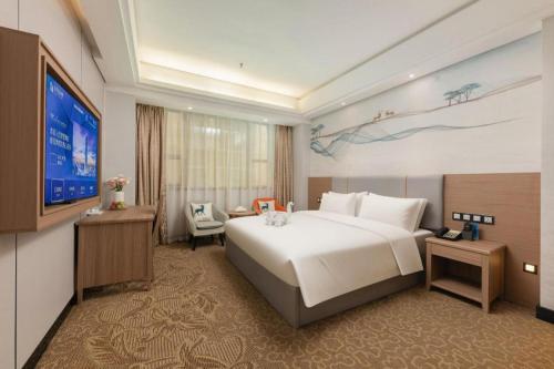 a hotel room with a large bed and a flat screen tv at Tong Da International Hotel in Zhangjiajie