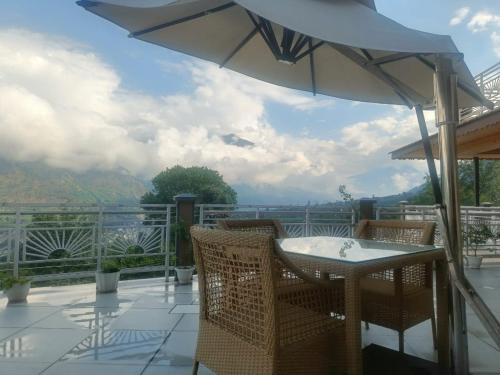 a patio with an umbrella and a table and chairs at Anand Vardhan Resorts in Manāli