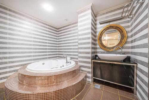 a bathroom with a tub and a sink and a mirror at Hotel S Shinchon in Seoul