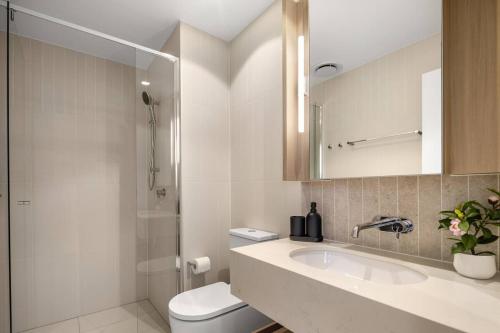 a bathroom with a toilet and a sink and a shower at New Luxe 2BR Queens Wharf Apt in Brisbane