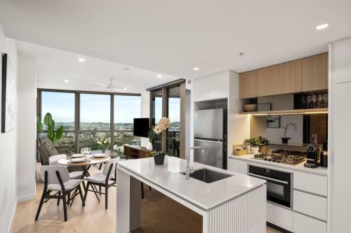 a white kitchen with a table and a dining room at New Luxe 2BR Queens Wharf Apt in Brisbane