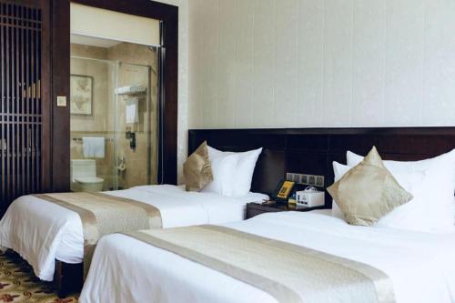 a hotel room with two beds and a mirror at Manhatton Hotel Beihai in Beihai