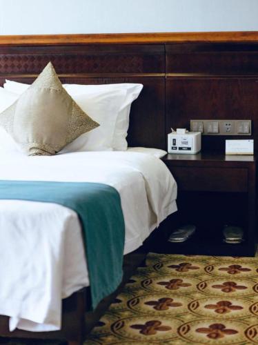 a bedroom with a bed with a wooden headboard at Manhatton Hotel Beihai in Beihai