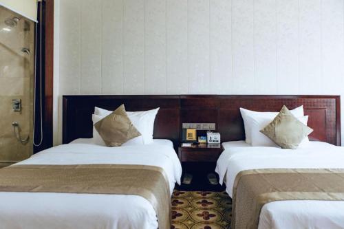 a hotel room with two beds with white sheets at Manhatton Hotel Beihai in Beihai